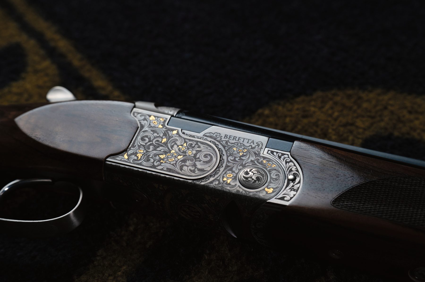 Side view of the Beretta 687 500 Years LE action showing the laser-etched floral engraving and gold highlights
