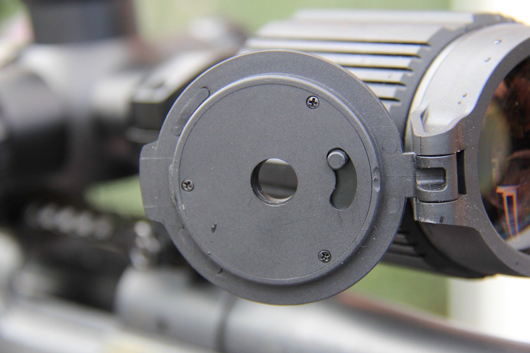 The flip-up lens cap of the RIX Tourer T50 4K closed, with its small sliding aperture open